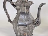 silver plated teapot with ornate design on a white background