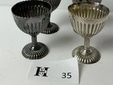 trois gobelets en argent posés sur une table, à côté d'une étiquette de prix
