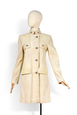 une photo d'un mannequin vêtu d'un manteau beige, posé sur un socle