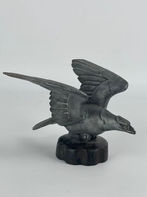 statue représentant un oiseau en plein vol, posée sur un socle en marbre, sur fond blanc