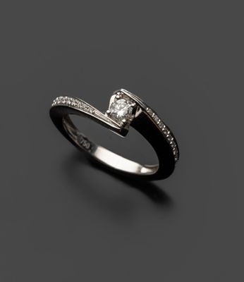 une bague en diamant noir et blanc posée sur une surface noire