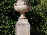 a stone urn sitting in the middle of the grass