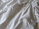 un lit défait, sur lequel sont posés des draps blancs et des oreillers