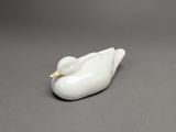 figurine de canard en porcelaine blanche posée sur une surface grise
