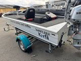 a small boat with a motor on a trailer in a parking lot