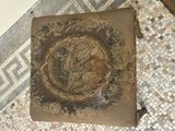 a brown pillow with a picture on it on a tiled floor