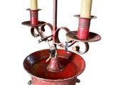 a red candle holder with two candles on it