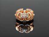 a close up of a gold ring with two diamonds on a black surface