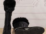 pair of black fur lined boots on a wooden floor