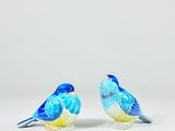 pair of blue and yellow bird figurines sitting on a white surface
