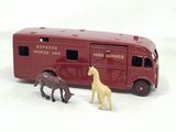 deux chevaux miniatures placés à côté d'un bus rouge