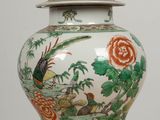 a white vase with a bird and flowers on it on a table