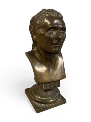 un buste en bronze représentant un homme, posé sur un socle, avec un fond blanc