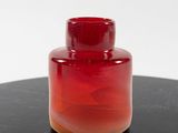 a red vase sitting on a black table with a white background