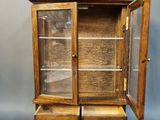an old wooden display cabinet with two drawers and a glass door