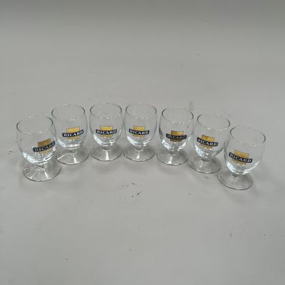 six verres aux bords dorés sont alignés sur une surface blanche