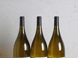 trois bouteilles de vin posées sur une table en bois à côté d'une bouteille de vin