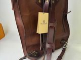 brown leather handbag with a tag on it sitting on a white surface