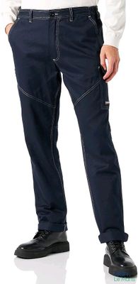 man in a white shirt and blue pants standing with his hands in his pockets
