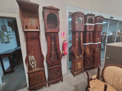 many wooden grandfather clocks on display in a room