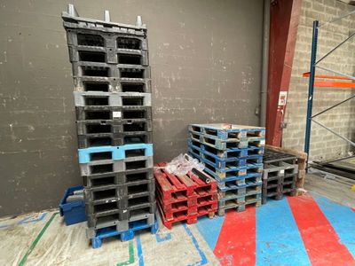 de nombreuses palettes empilées au sol dans un entrepôt