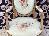 une vieille chaise dont l'assise est recouverte d'un tissu à motifs floraux, posée sur un tapis