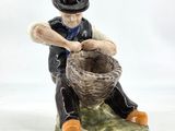 a figurine of a man sitting on a rock with a basket