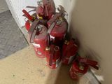 several red fire extinguisors are lined up against a wall