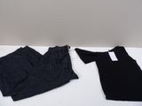 two pairs of black pants and a black shirt on a white table