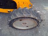 a tractor tire that is sitting on the ground next to a yellow tractor