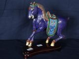 une figurine représentant un cheval bleu posée sur un socle en bois