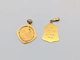 a close up of two gold charms on a white surface