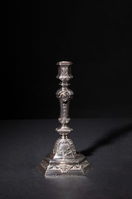 a silver candle holder on a black surface with a black background