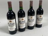 quatre bouteilles de vin sont alignées sur une surface blanche
