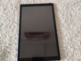 une tablette noire posée sur une couverture blanche