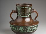a brown and green vase sitting on a table
