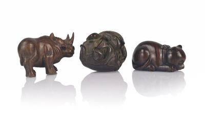 three bronze figurines of rhinos and a rhino on a white surface
