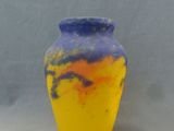 un vase jaune et bleu posé sur une surface blanche, avec un arrière-plan gris