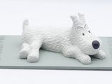 a white dog figurine sitting on top of a mat