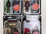 three star wars action figures sit in their packages on a white surface
