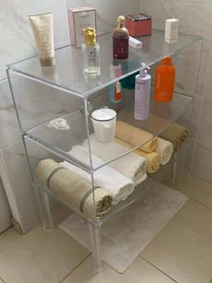 une étagère en verre sur laquelle sont posés des serviettes, des savons et d'autres articles