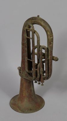an old brass musical instrument on a stand on a white surface