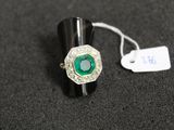 un gros plan d'une bague ornée d'une pierre verte sur un fond noir