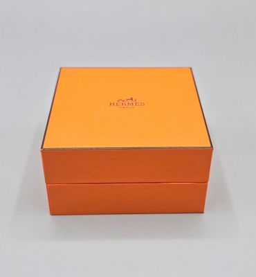 une boîte orange portant un logo, posée sur une surface blanche
