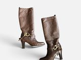 a pair of brown leather boots with a gold buckle on the heel