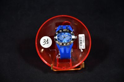 une montre bleue dans un écrin rouge posé sur une surface noire