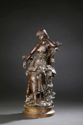 une statue en bronze représentant une femme assise sur un rocher