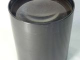 une tasse noire avec un couvercle noir posée sur une table blanche