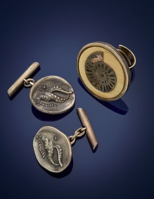 trois boutons de manchette en argent et une pièce de monnaie sur fond bleu