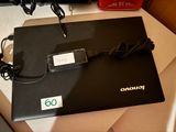 un ordinateur portable noir posé sur un bureau, avec son chargeur